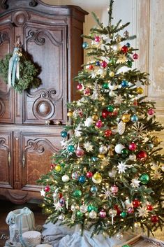 a decorated christmas tree in front of a dresser