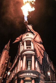 a dragon statue on top of a building at night with the sky in the background