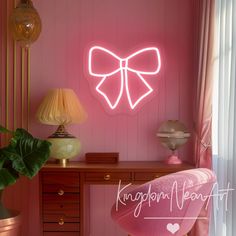 a pink room with a desk, chair and large neon bow sign on the wall