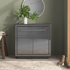 a grey cabinet sitting next to a mirror and wooden stool with shoes on the floor