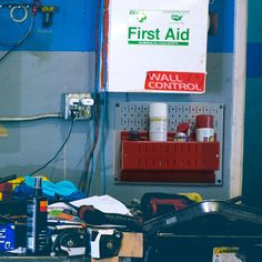 the first aid sign is hanging on the wall next to some tools and other items