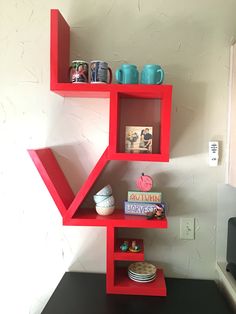 a red shelf that has some cups and plates on top of it in the corner