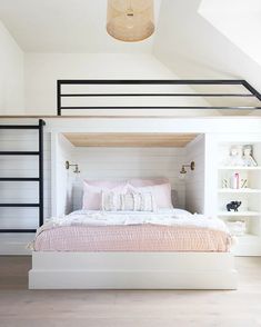 a white bed sitting under a light next to a book shelf