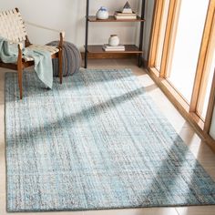 a blue rug in a room with a chair and bookshelf on the wall