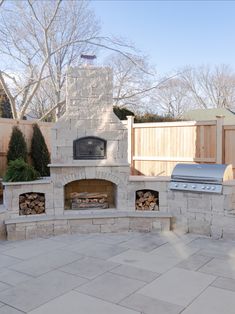 an outdoor fireplace and grill in the middle of a patio with stone pavers around it