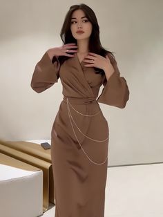 Thoughtfully designed to exude elegance, this taupe dress is a celebration of modern femininity. With voluminous bishop sleeves and a plunging neckline, it strikes a balance between bold and demure. The dress cinches at the waist with a unique chain detail, creating a flattering silhouette that accentuates the natural curves. Crafted from a sumptuous fabric with a hint of sheen, this piece is perfect for those who seek a blend of contemporary design and timeless appeal. Seasons: Spring/Autumn Ty Socialite Style, Rhinestone Chain, Satin Maxi, Satin Maxi Dress, Long Red, Looks Chic, Style Maxi Dress, Classy Dress, Waist Dress