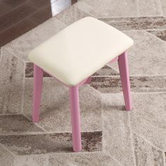 a pink and white stool sitting on top of a carpeted floor next to a rug