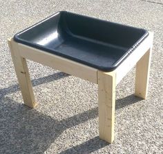 a small wooden table with a black plastic bowl on it's top and legs