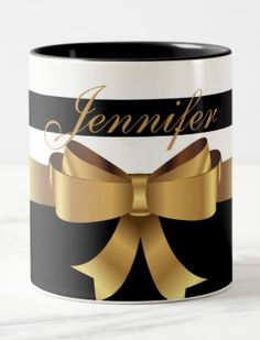 a black and white striped mug with a gold bow on the side that says, jennyifer