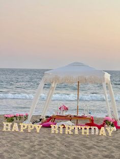 a happy birthday message on the beach with an umbrella and table set up for a party