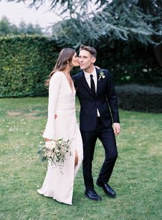 a man in a suit and tie standing next to a woman in a white dress