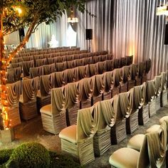 rows of chairs with drapes on them in front of a tree and stage lights