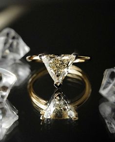 a yellow diamond ring sitting on top of a table next to some ice cubes