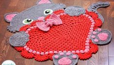 a crocheted rug with a cat holding a heart on it's back