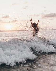 a person riding a wave on top of a surfboard in the ocean at sunset