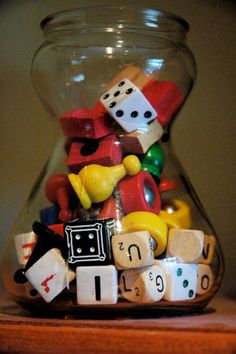 a glass vase filled with lots of dice and wooden blocks