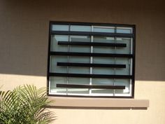 a window with blinds on the side of it and a potted plant next to it