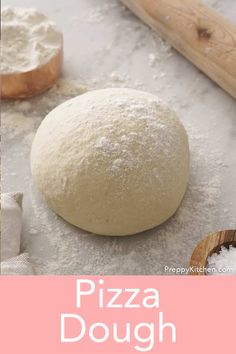 a pizza dough sitting on top of a table next to wooden spoons and flour