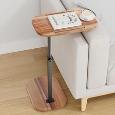 a small wooden table with a magazine on it next to a white couch in a living room