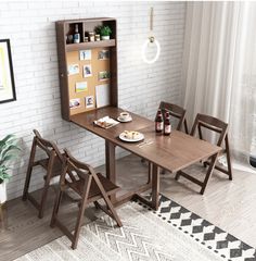 a wooden table and chairs in front of a white brick wall with pictures on it