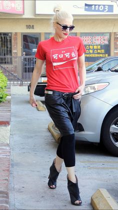 a woman in red shirt and black pants walking on sidewalk