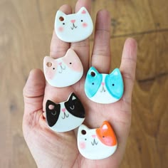 four small ceramic cats sitting in the palm of someone's hand