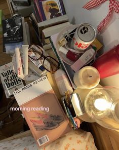 an assortment of items sitting on top of a bed next to a lamp and books