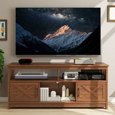 a flat screen tv mounted on the wall above a wooden entertainment center with books and other items