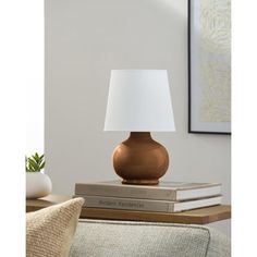 a table lamp sitting on top of a stack of books next to a couch and chair