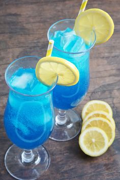 two glasses filled with blue liquid and lemon slices