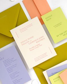 the wedding stationery is laid out on top of different colored envelopes and cards