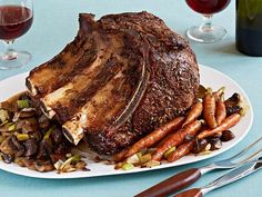 a large piece of meat sitting on top of a white plate next to carrots