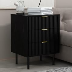 a black and gold nightstand with books on it next to a couch in a living room