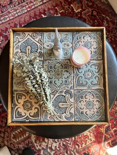 a small tray with some flowers and a candle on it sitting on top of a table