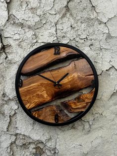 a clock made out of wood sitting on the side of a stone wall with peeling paint