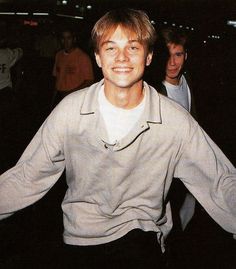 a young man is smiling and holding his arms out in front of him while others are standing behind him