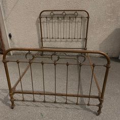 an old iron bed frame with no headboard and foot board is sitting in front of a stucco wall