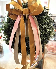 a wreath with pink and gold ribbons hanging from it's centerpiece in a store