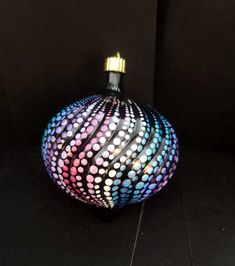 a colorful ball sitting on top of a black floor next to a light bulb with dots painted on it