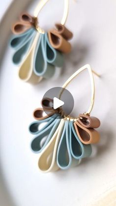 two pairs of earrings are shown on a white surface, one is blue and the other is brown