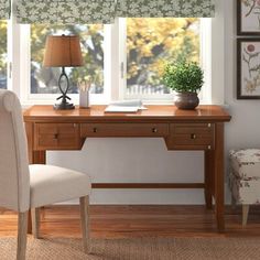 a desk and chair in front of a window with green floral curtains on the windowsill