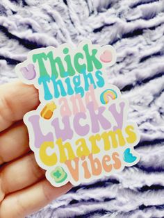 a hand holding a sticker that says thick thighs and lucky charms vibes