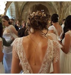 the back of a woman's wedding dress with gold leaves on her head and shoulders