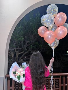 a woman holding flowers and balloons in her hand