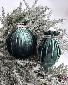 two green ornaments sitting on top of a tree