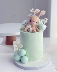 a cake decorated with an easter bunny sitting on top of it's side and eggs around the base