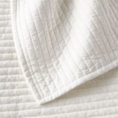 an unmade bed with white sheets and pillows on top of it, close up