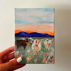 a painting of three cows in a field with mountains in the background, painted on canvas