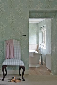 a bathroom with green wallpaper and a white bathtub next to a radiator