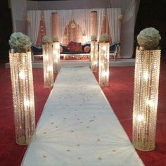 the aisle is decorated with white flowers and gold beaded columns for an elegant wedding